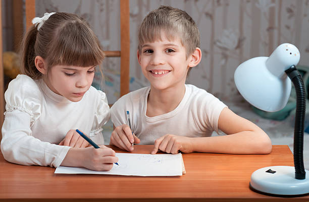 Радостный мальчик и девочка изучают правила письма и орфографии в школе